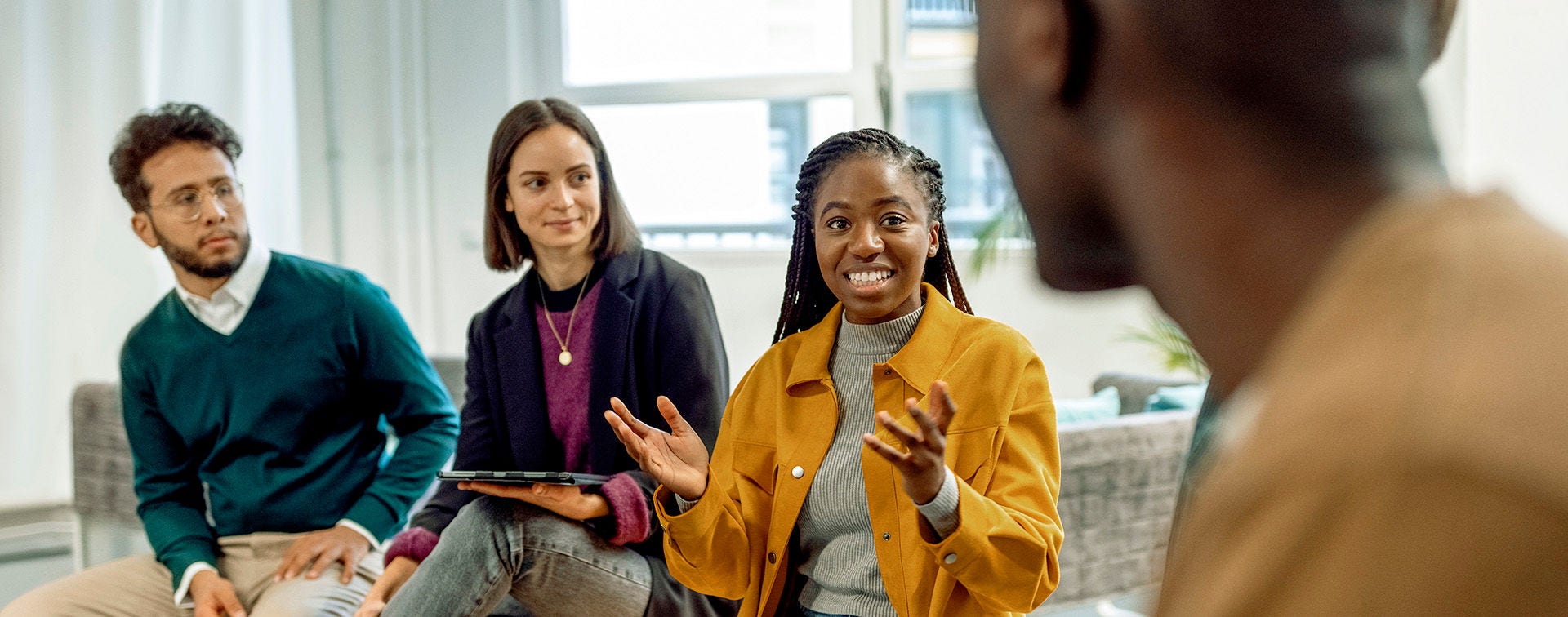 A diverse team of employees discuss a project in an office meeting room.